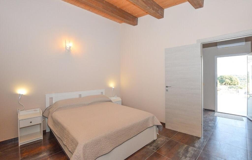 La Camera Tripla con il letto matrimoniale, le travi in legno e la porta aperta sulla campagna