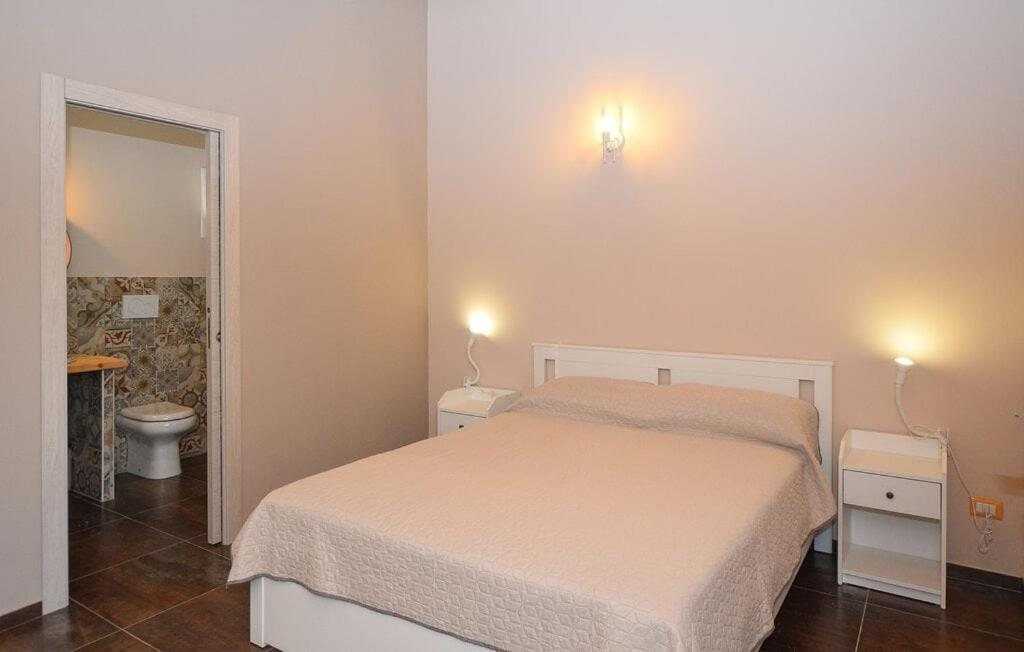 Il letto matrimoniale della Camera Tripla con le applique accese e la porta del bagno