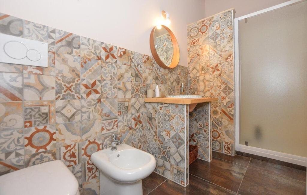 Il bagno della Camera Tripla con le piastrelle decorate, il lavabo su piano in legno e il box doccia