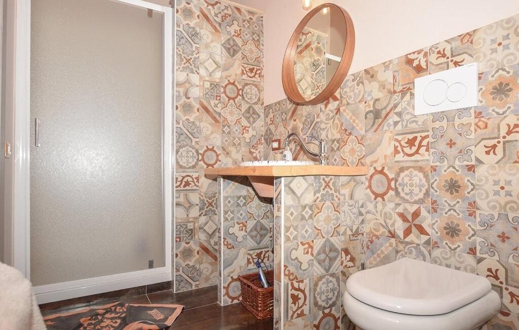 Il lavabo su mensola in legno e lo specchio tondo nel bagno della Camera Tripla