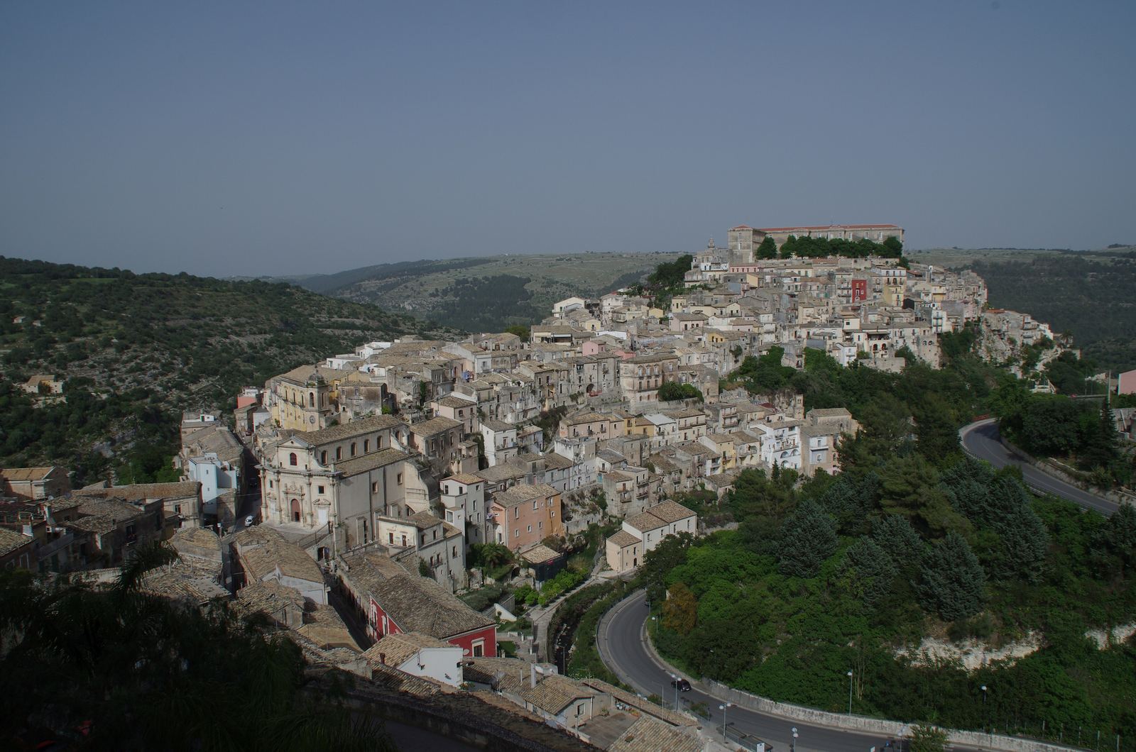 Veduta dall'alto di Ragusa Ibla adagiata sul colle, con la strada tornante nella vallata.