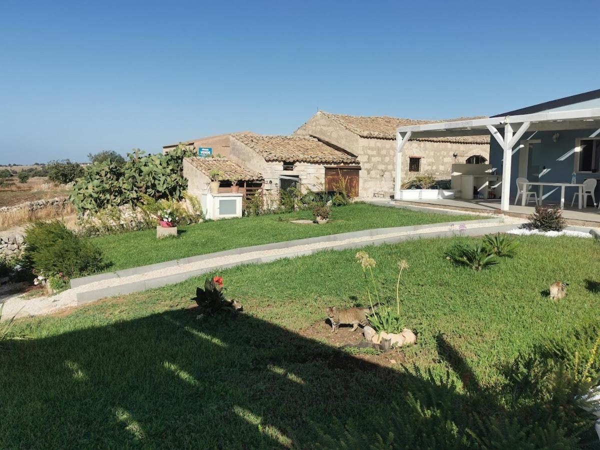 Il prato davanti alla villa in pietra, con la veranda e il pergolato bianco