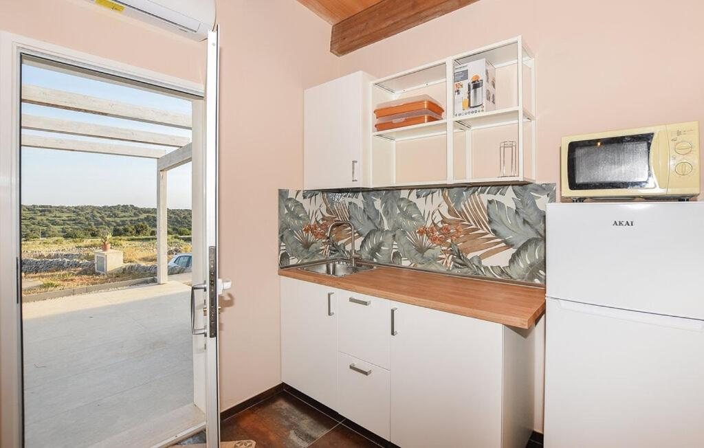 La cucina con il piano in legno, il frigorifero e la porta vetrata sulla veranda