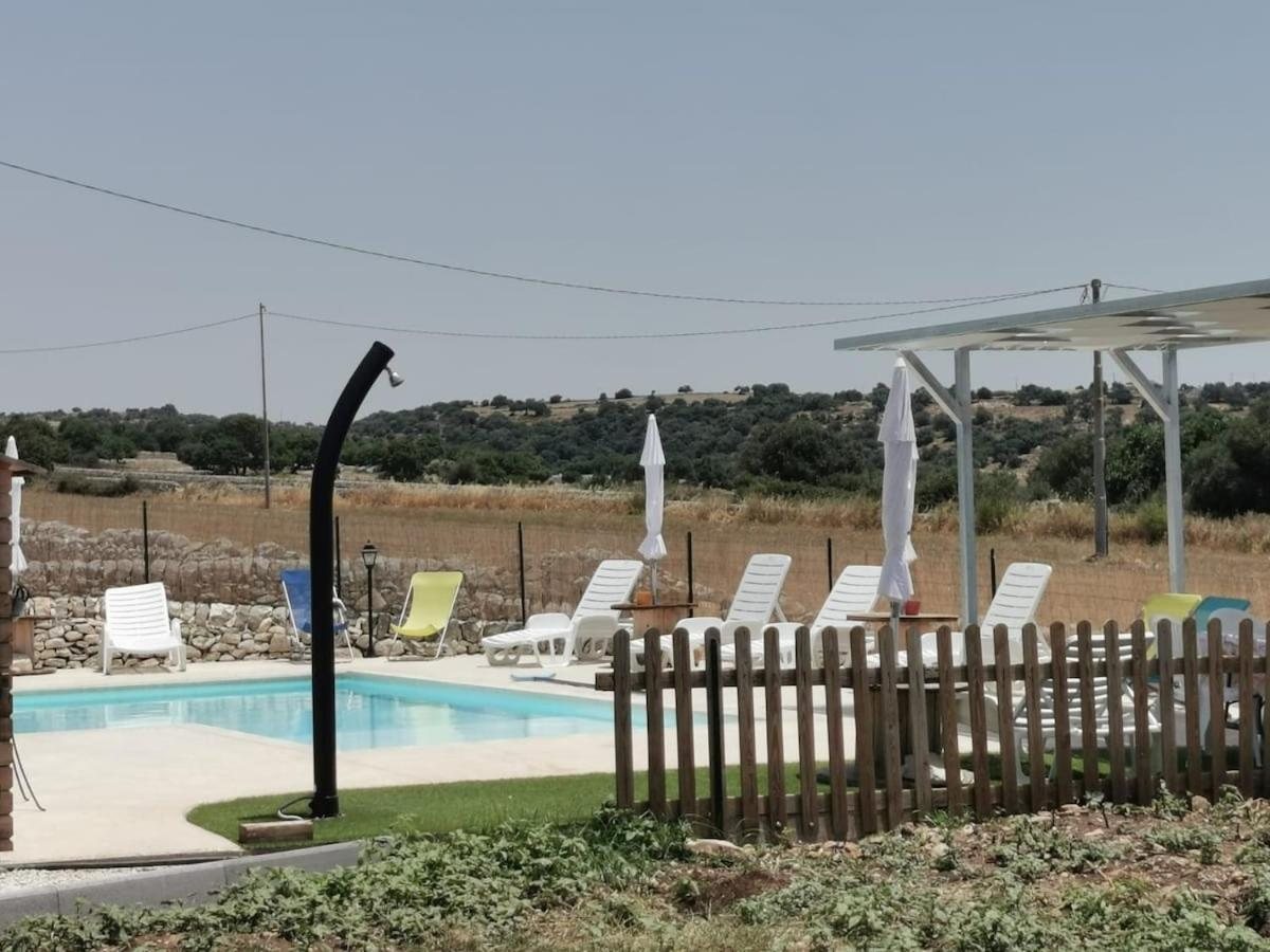 La doccia esterna accanto alla piscina, con la staccionata in legno e i lettini