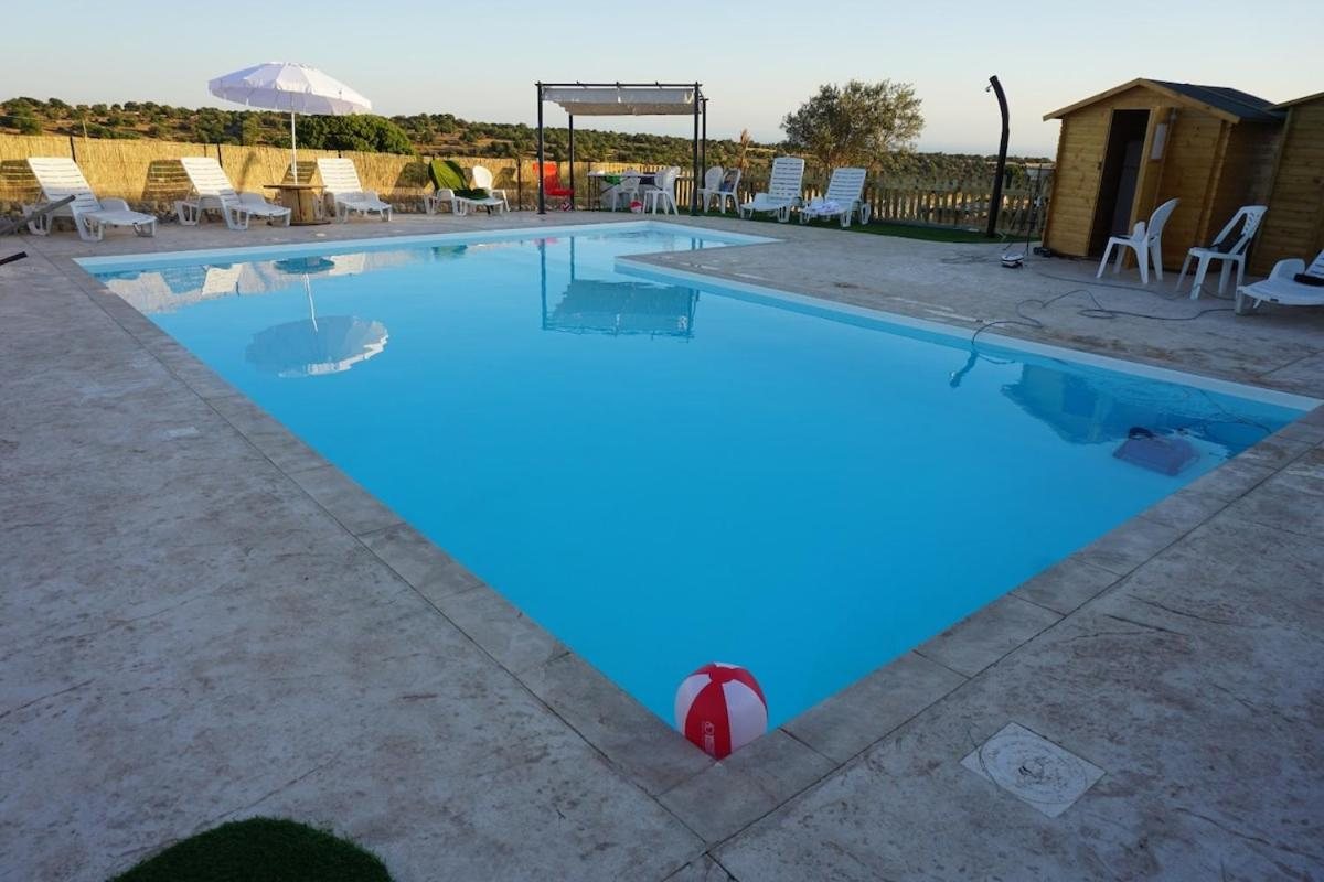 La piscina a forma di L con il pallone sul bordo e i lettini