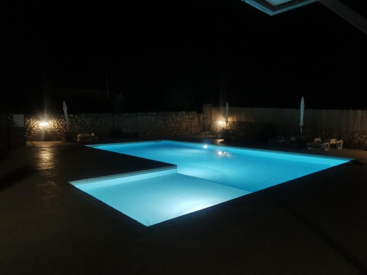 La piscina illuminata di notte, con la zona bassa e le luci del giardino